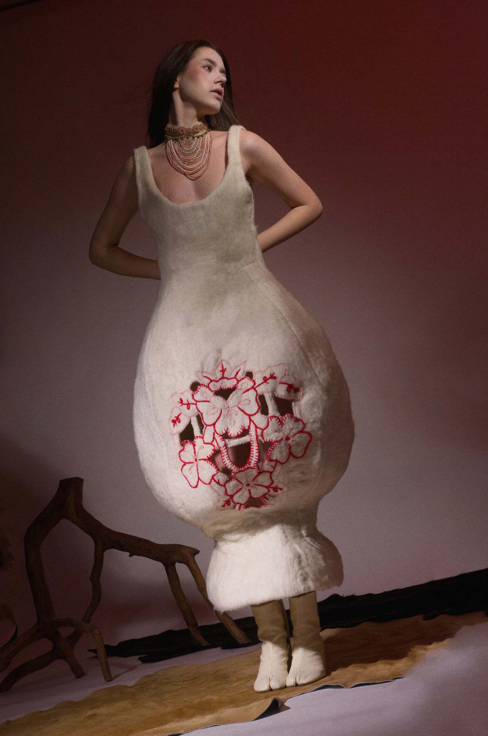 Sculptural ivory garment with hand-finished red-pink embroidery