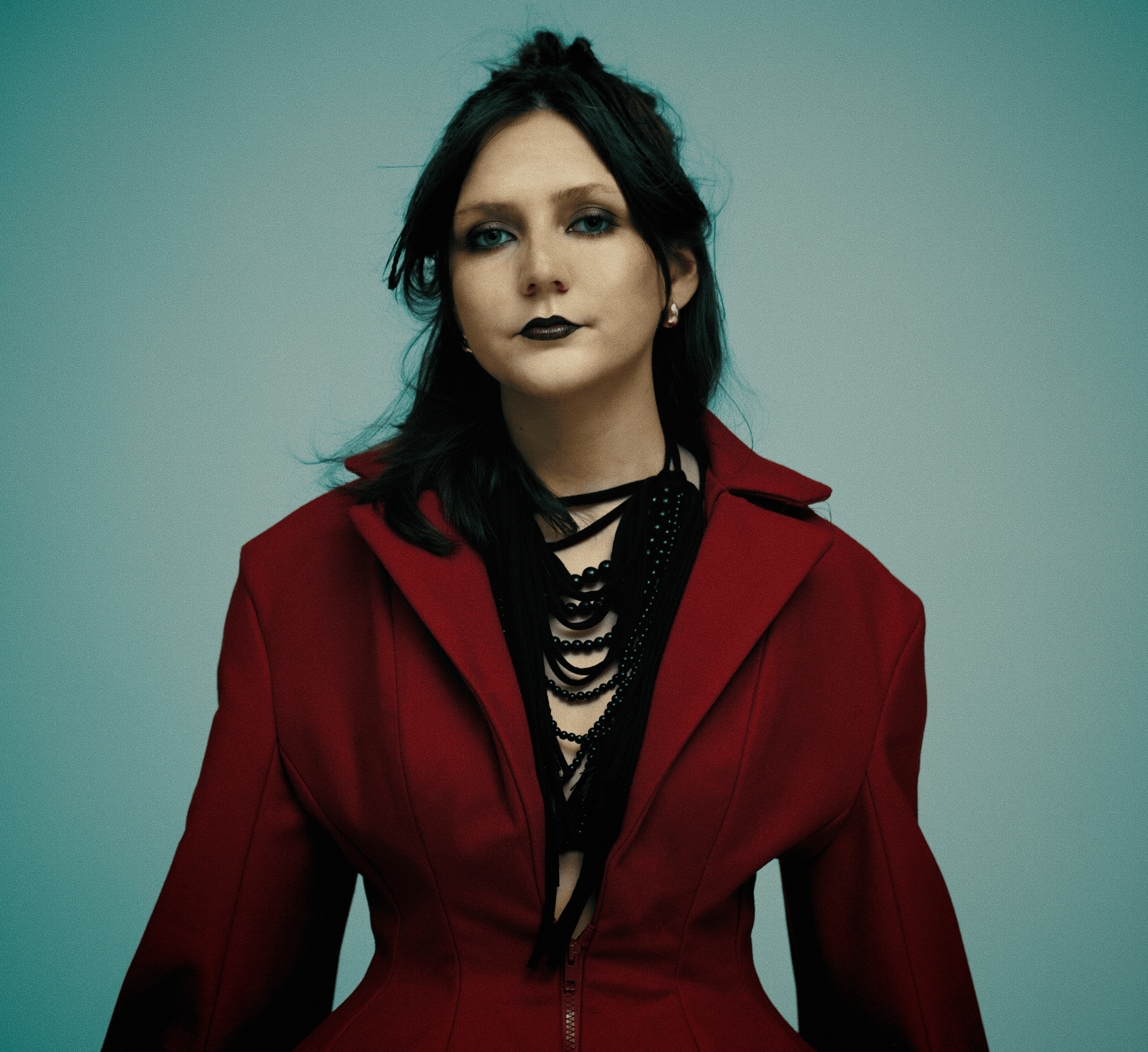 Portrait of the designer in a deep red tailored jacket