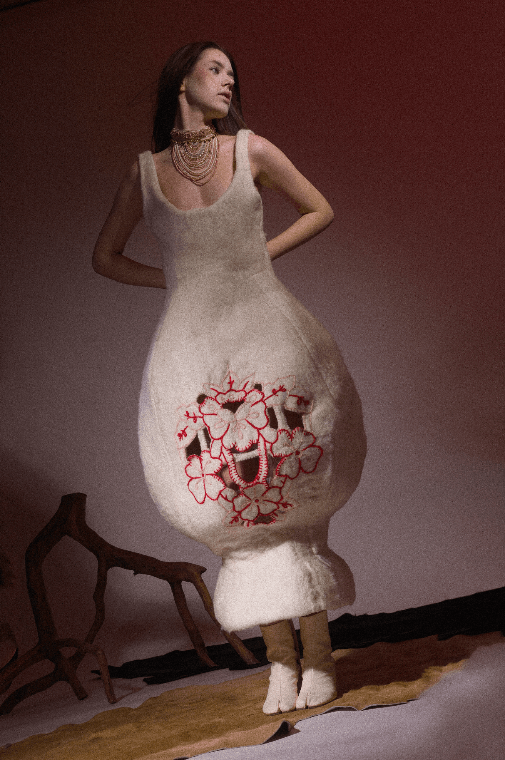 Sculptural ivory garment with hand-finished red-pink embroidery